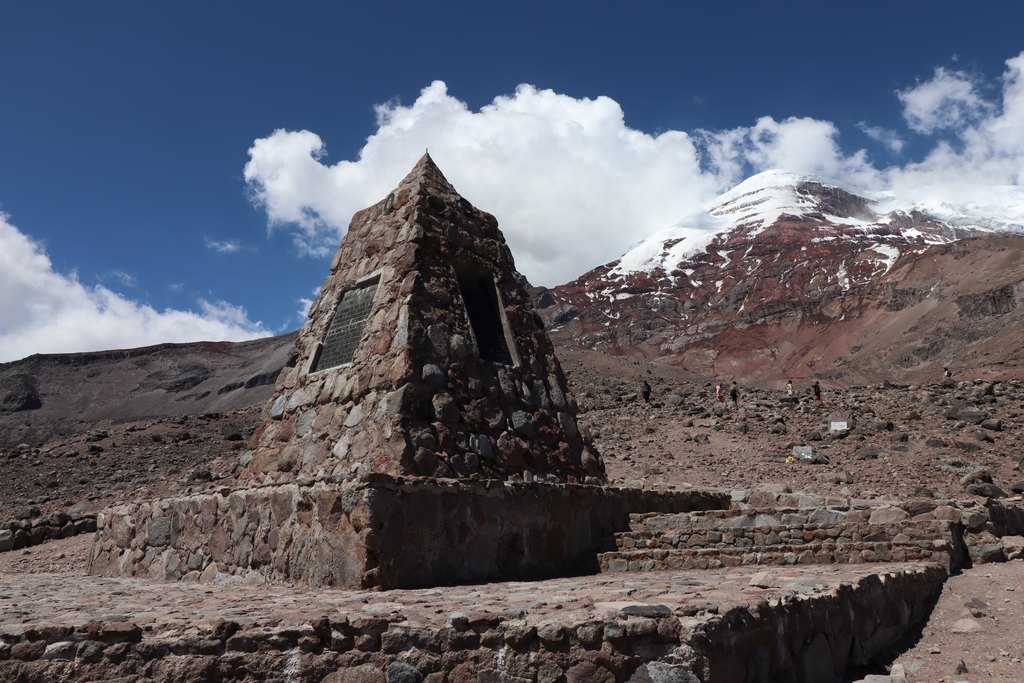 Steinpyramiede, welche die Himmelsrichtungen zeigt, im Hintergrund der Chimborazo.