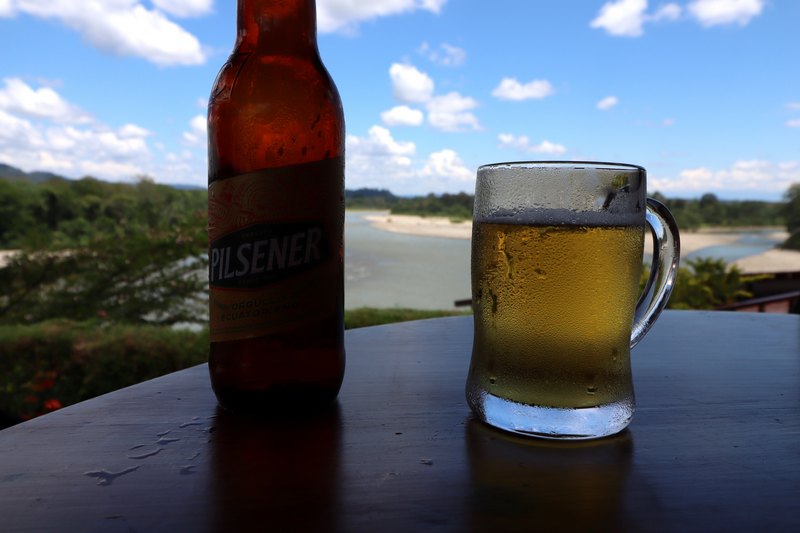 Bierglas mit Wasserperlen, blauer Himmel und Regenwasd im Hintergrund