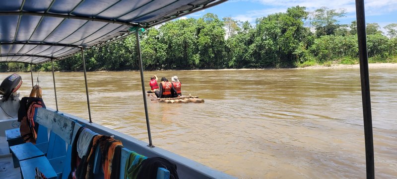 Menschen sitzen auf einem Floos und treiben auf dem Rio Napo