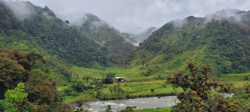 kleine Hütte am Fluss dahinter Hügel im Nebel